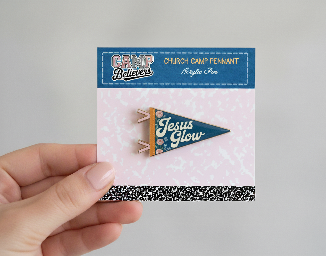 Hand holding a card with a 'Jesus Glow' pennant pin and 'Camp Believers' branding.